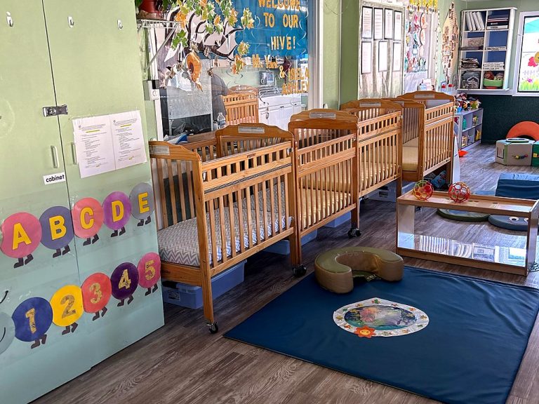 Infant room with cribs and a tummy-time mat at a Small Miracles daycare in Tucson
