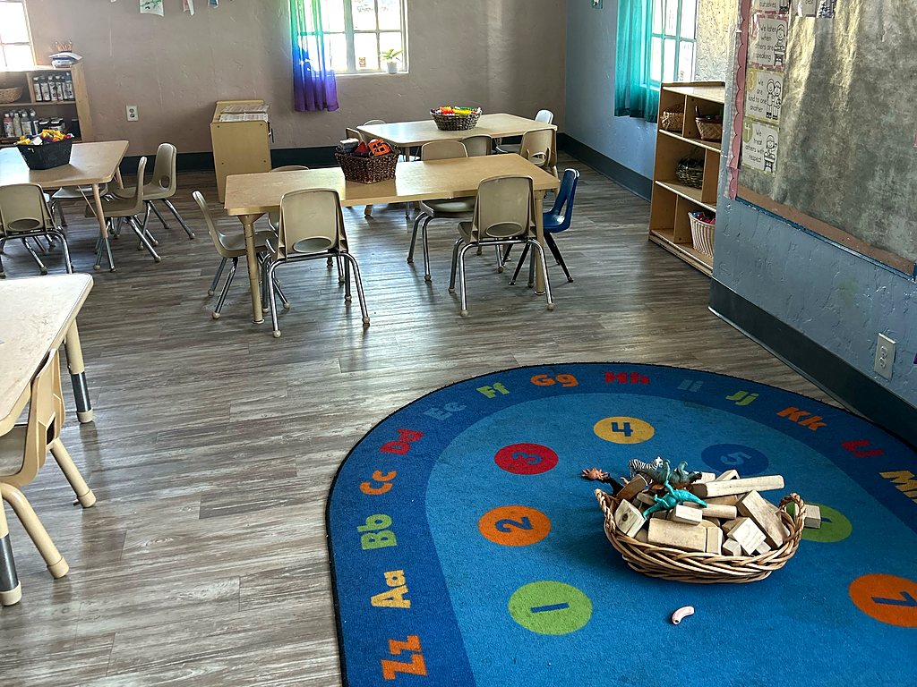 Preschool classroom at a Small Miracles daycare in Tucson with an alphabet circle-time rug, block basket and child-size tables